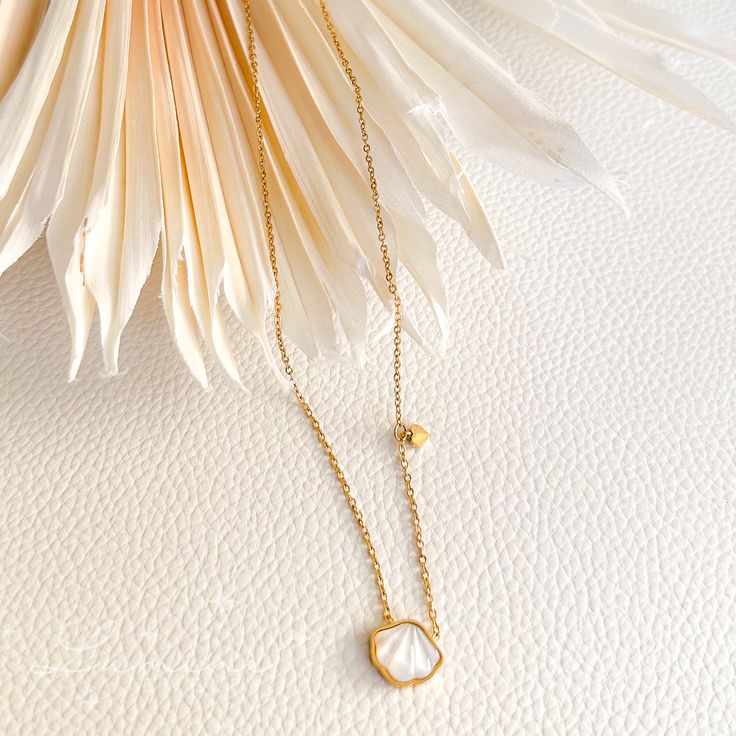 Go ahead and make a statement without saying a word with this cute and dainty Snow Shell Necklace! The tiny heart charm attached gives the necklace that subtle elegance. Material: 18k gold plated on stainless steel Pendant: Natural cowrie shell Length: Dainty Shell Necklace With Pearl Charm, Gold Shell Necklace With Delicate Chain As Gift, Gold Shell Necklace With Delicate Chain For Gifts, White Minimalist Gold-plated Charm Necklaces, Dainty White Tarnish Resistant Charm Necklace, Minimalist Mother Of Pearl Necklace As Gift, Minimalist Mother Of Pearl Necklace As A Gift, Minimalist Mother Of Pearl Necklace For Gift, Dainty Gold Mother Of Pearl Necklace