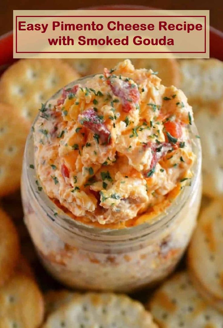 a jar filled with cheesy potato salad next to crackers