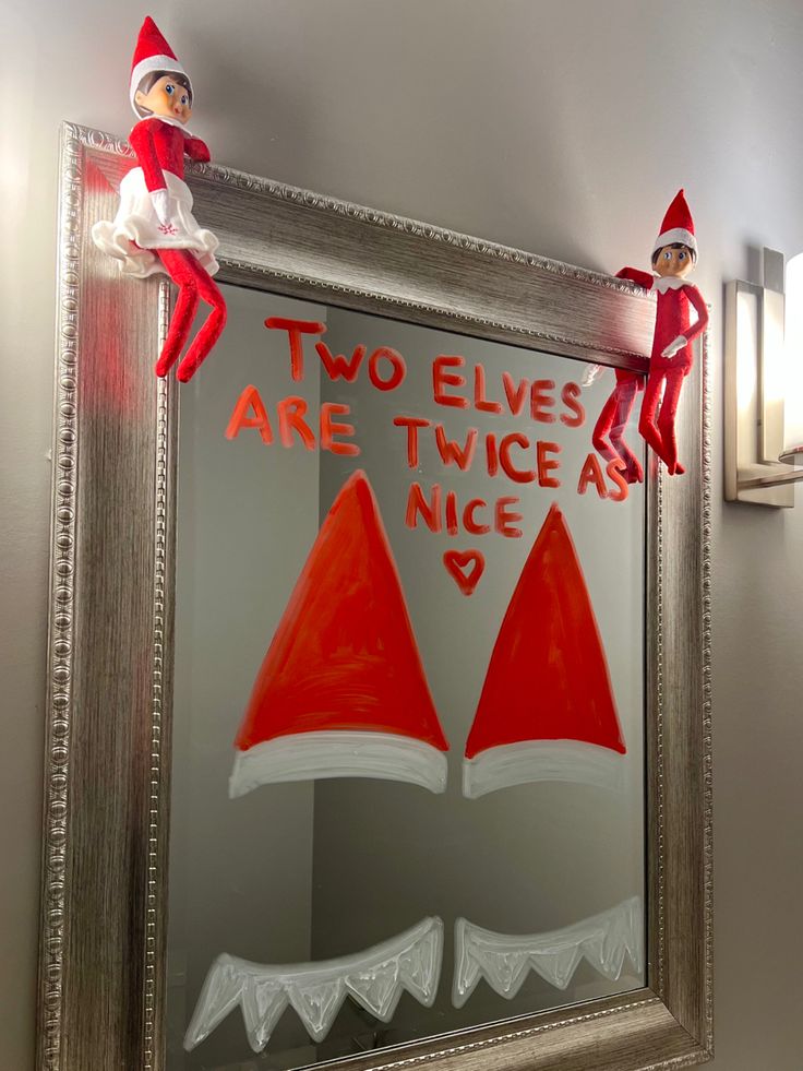 two elfs are sitting on top of a mirror with the words two elves are twice as nice