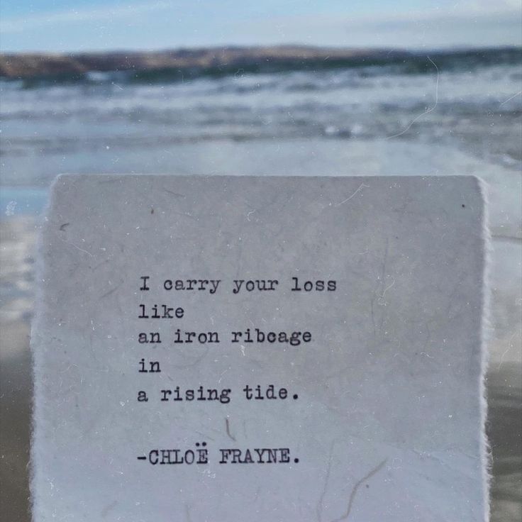 a piece of paper with a quote on it sitting in front of the ocean and water