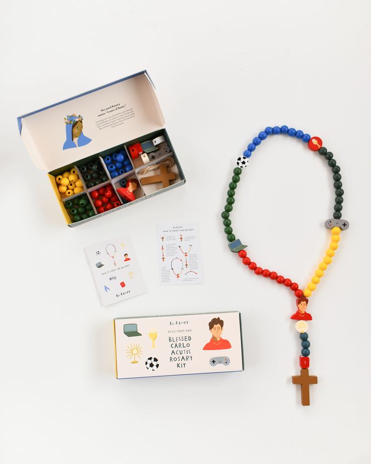 a box with beads and a cross on it next to a rosary, card game and other items