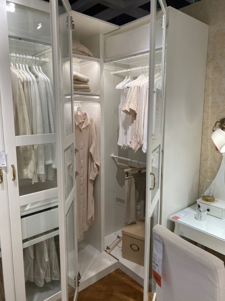 an open closet with clothes hanging on hangers and a lamp next to the closet