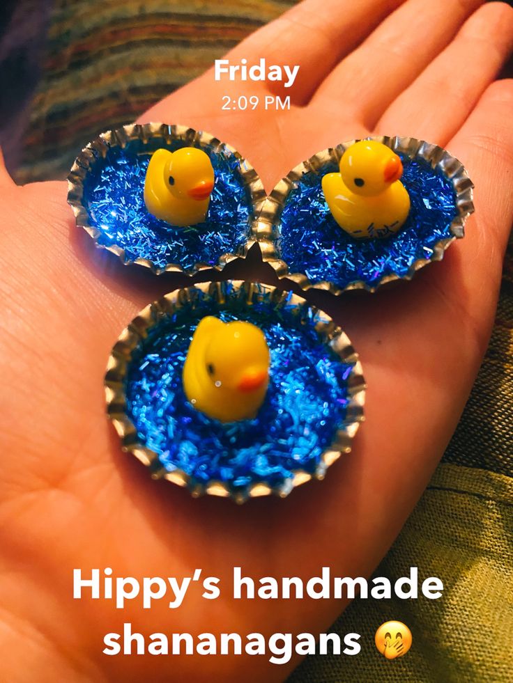 three little yellow rubber ducks in a blue cupcake tinsel dish on someone's hand