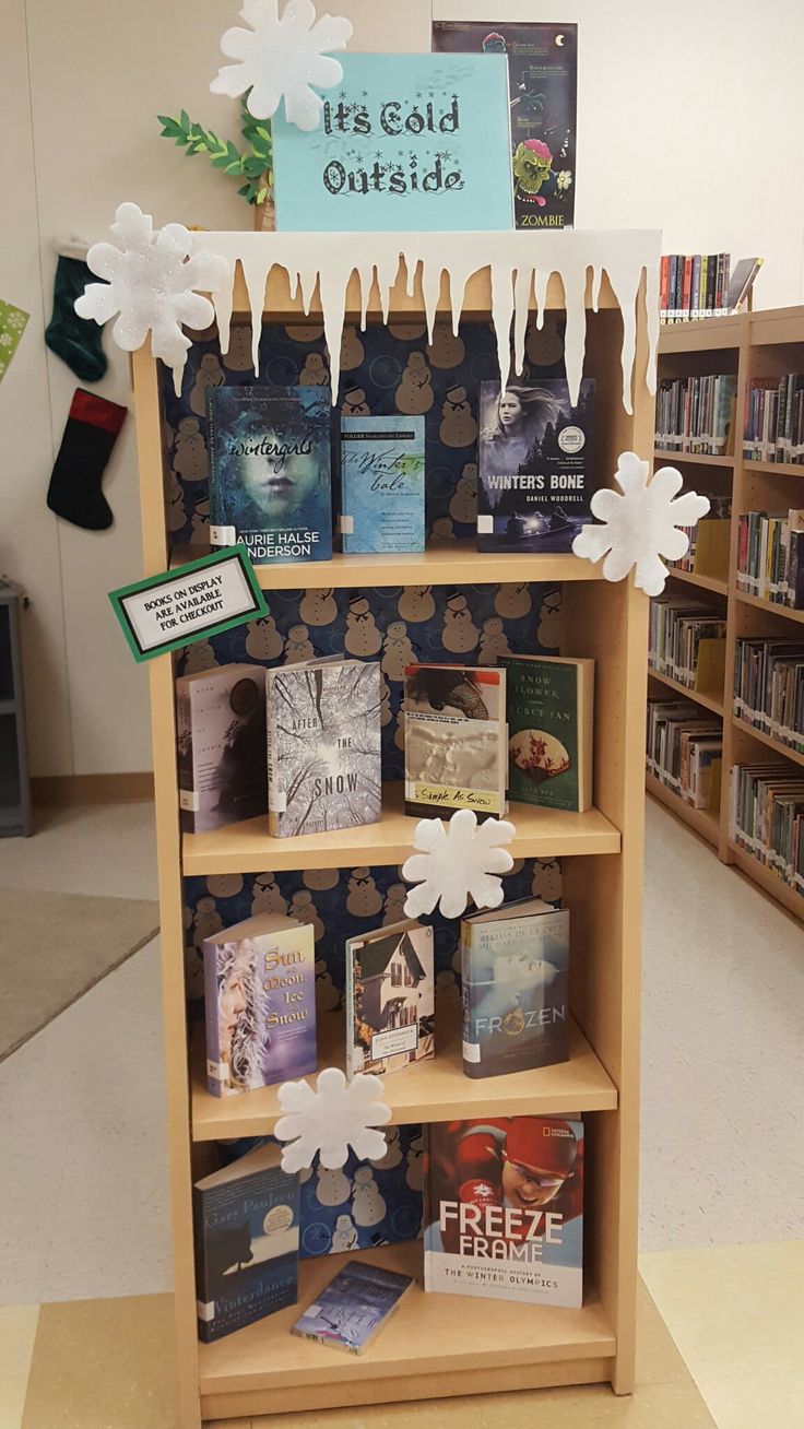 a book shelf filled with lots of books and paper snowflakes hanging from it's sides