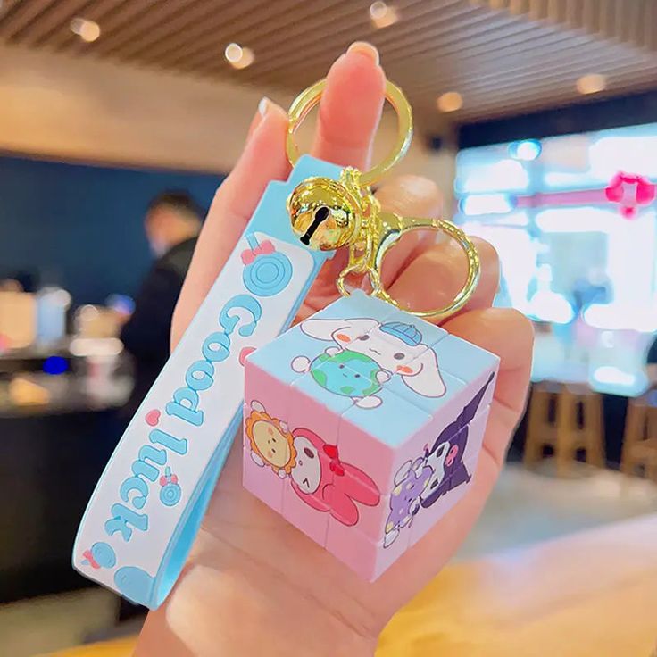 a person holding up a small keychain with an animal themed box attached to it