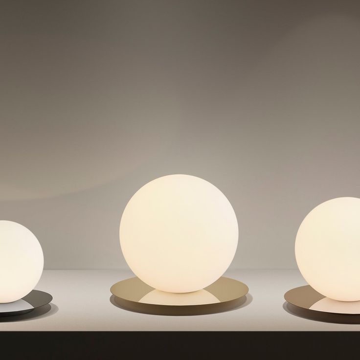 three white balls sitting on top of each other in front of a gray wall and floor