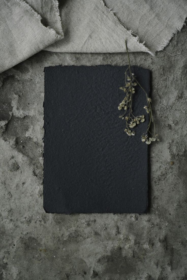 a piece of black paper sitting on top of a table next to a flower arrangement