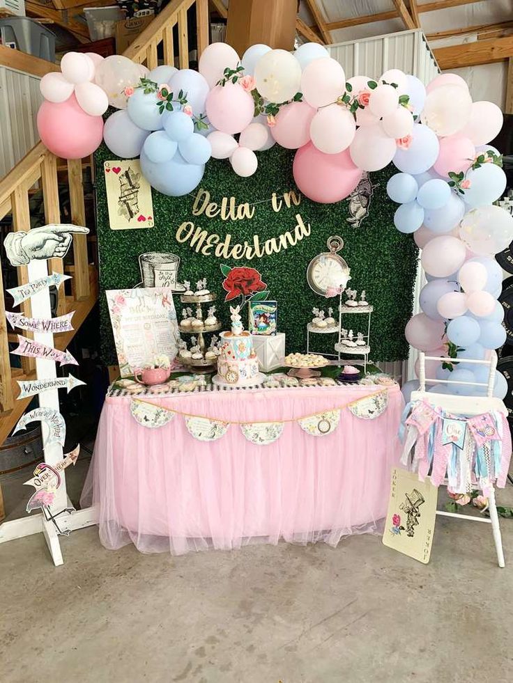 a table topped with balloons and desserts under a staircase case at a princess themed birthday party