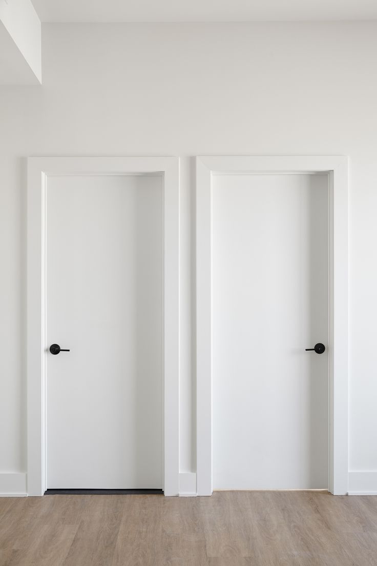 an empty room with two open doors on the wall and wood flooring in front of it