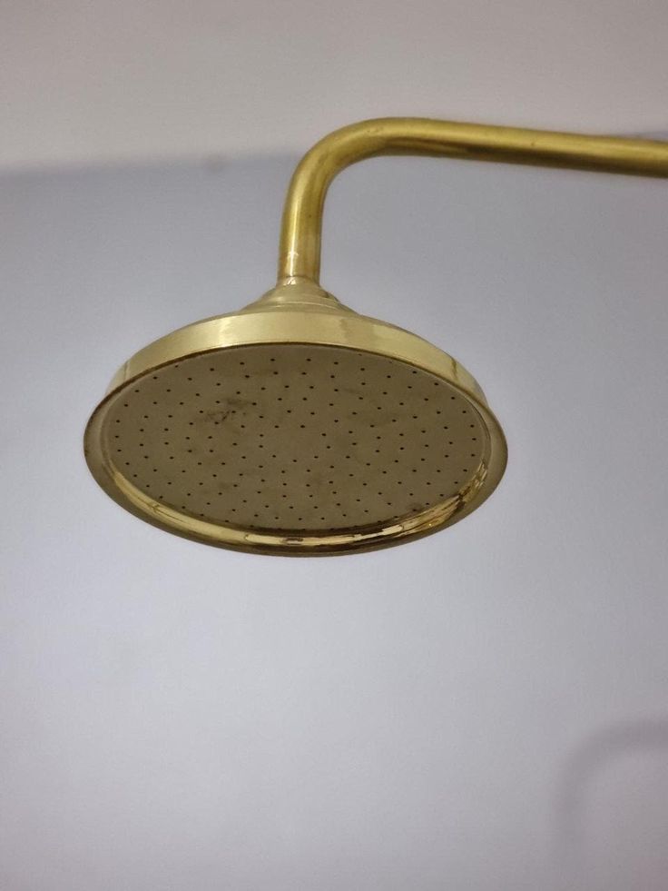 a brass shower head on a white wall