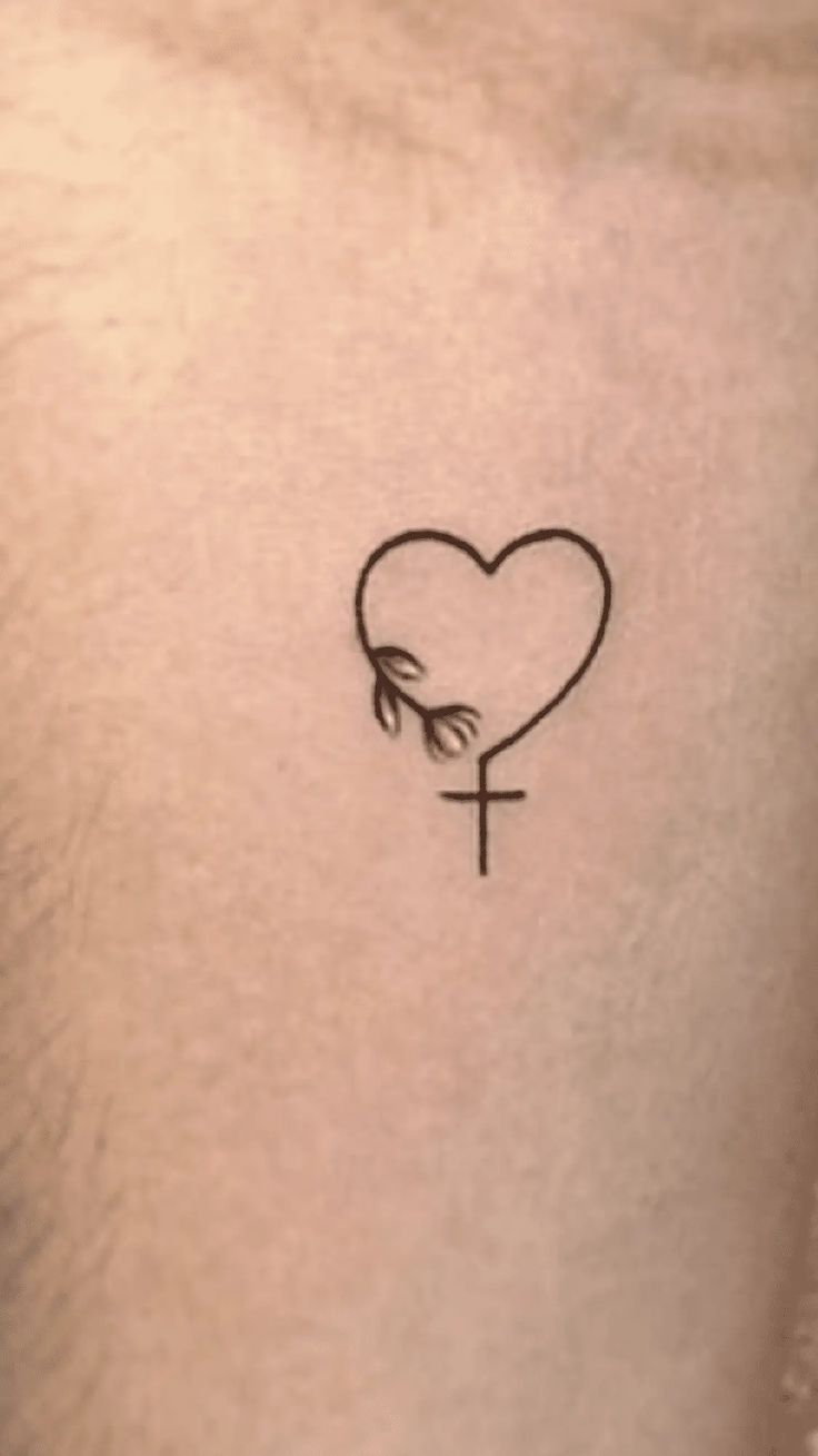 a small cross and heart tattoo on the chest