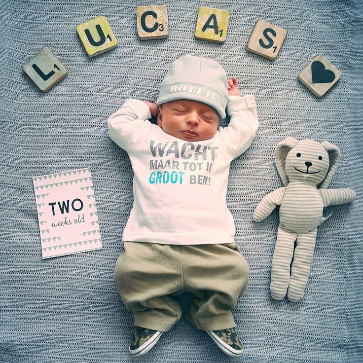 a baby laying on top of a blanket next to a teddy bear and wooden blocks