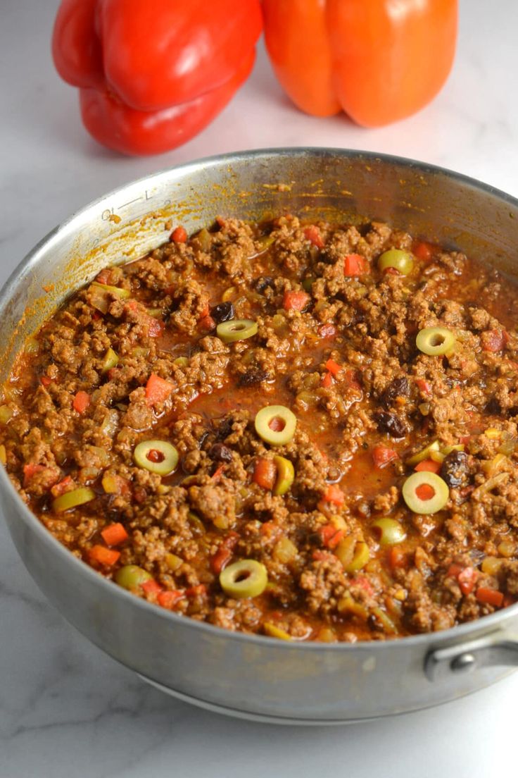 a pan filled with meat and vegetables next to tomatoes