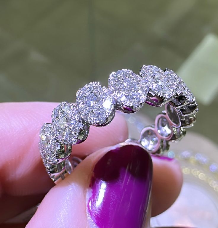 a woman's hand holding a purple manicured nail and ring with diamonds on it