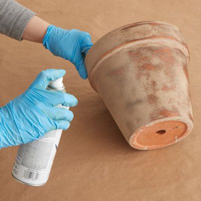 a person in blue gloves holding a spray bottle next to a roll of toilet paper