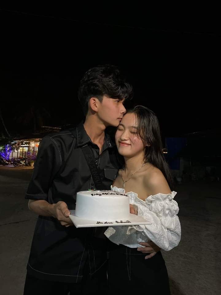 a man and woman standing next to each other with a cake in front of them