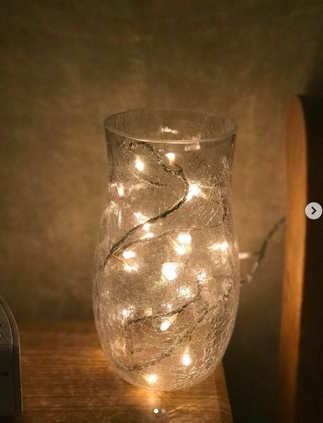 a glass filled with lights sitting on top of a wooden table