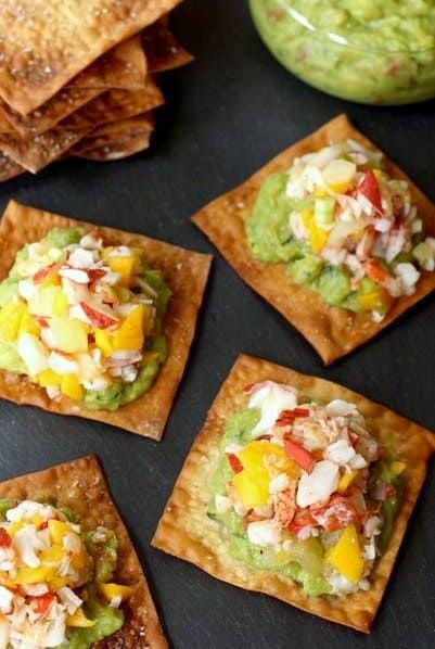 small crackers topped with guacamole and other toppings on a table