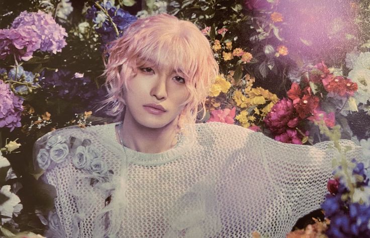 a woman with pink hair sitting in front of flowers