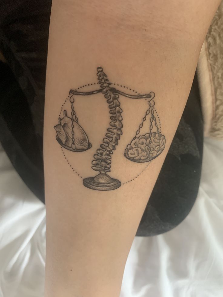 a woman's leg with a tattoo on it that has a scale and hour