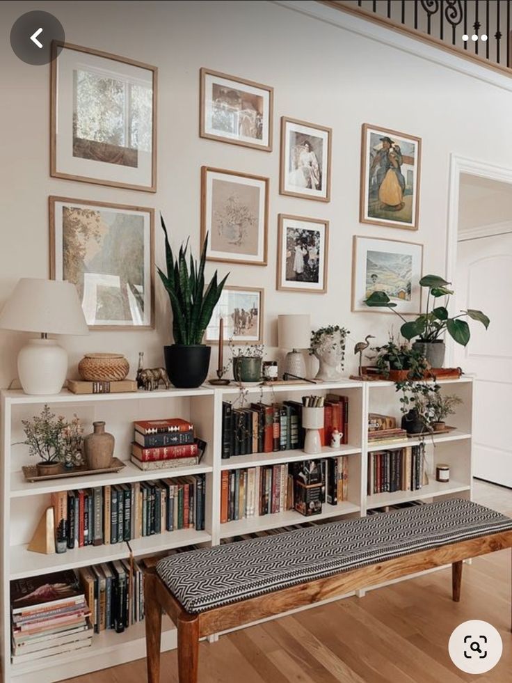 a bookshelf filled with lots of books next to a stair case covered in pictures