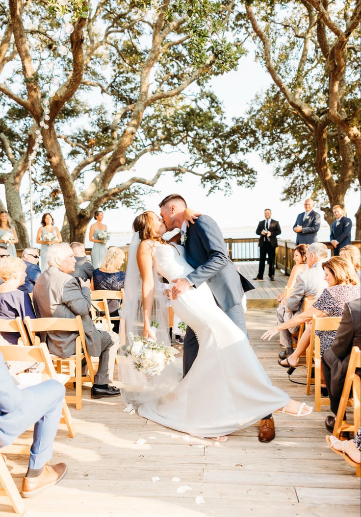 a bride and groom kiss as they walk down the aisle at their outdoor wedding ceremony