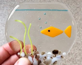 a hand holding a small glass fish bowl