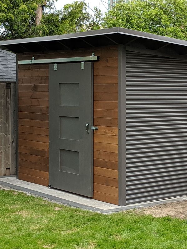 a small shed with two doors on the side and one door open in front of it