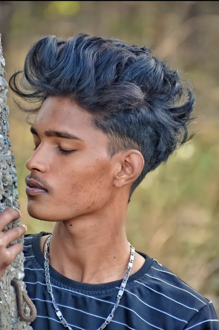 a young man leaning against a tree with his eyes closed