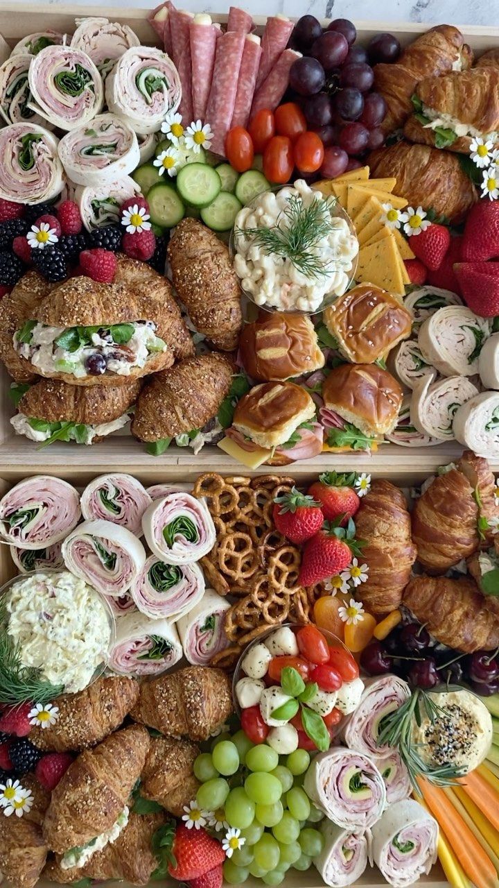 two trays filled with different types of pastries and fruit on top of each other