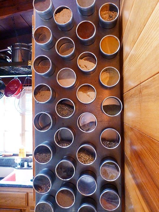 a metal rack filled with lots of different kinds of spices on top of a wooden wall