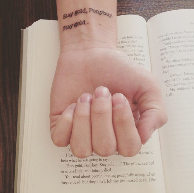 a person's hand holding an open book with writing on the inside of it