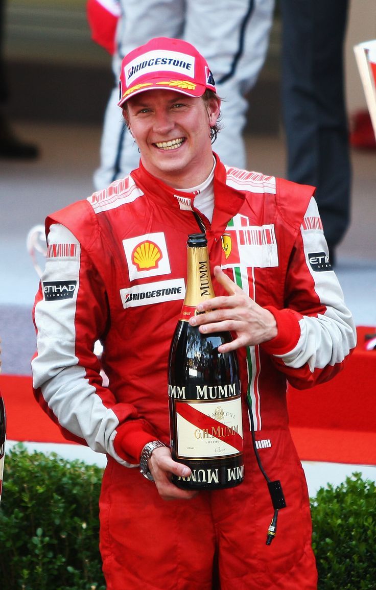 a man in a racing suit holding a bottle of champagne