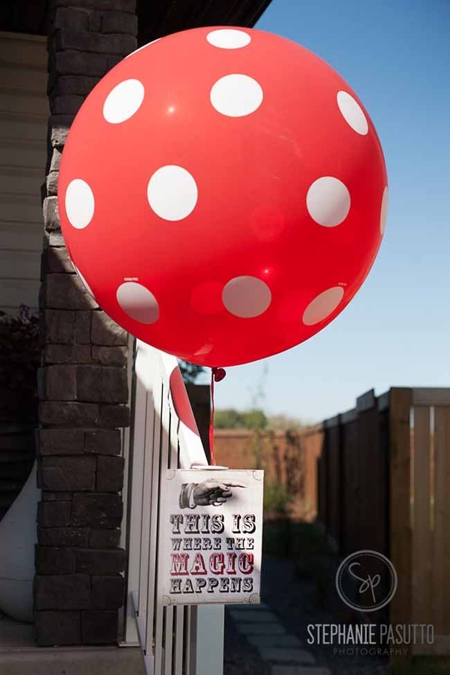 a red balloon with white polka dots hanging from the side of a house in front of a brick building