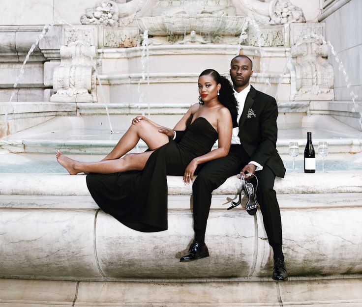 a man and woman sitting next to each other in front of a fountain