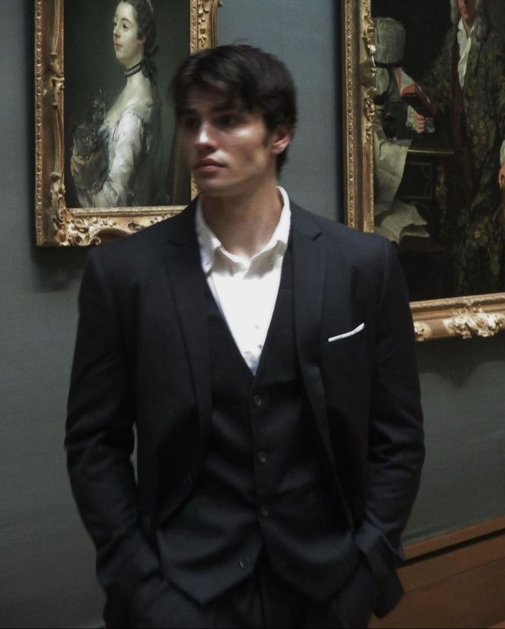 a man standing in front of two paintings with one painting on the wall behind him