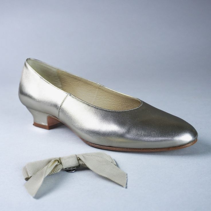 a pair of silver shoes with a white bow