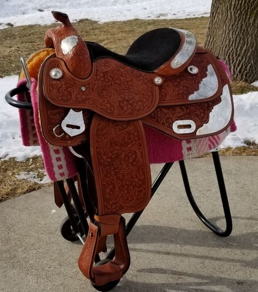 a brown and white horse saddle sitting on top of a sidewalk next to a tree