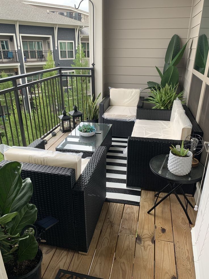 a balcony with black wicker furniture and potted plants