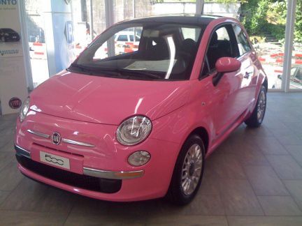 a pink car is parked in a showroom