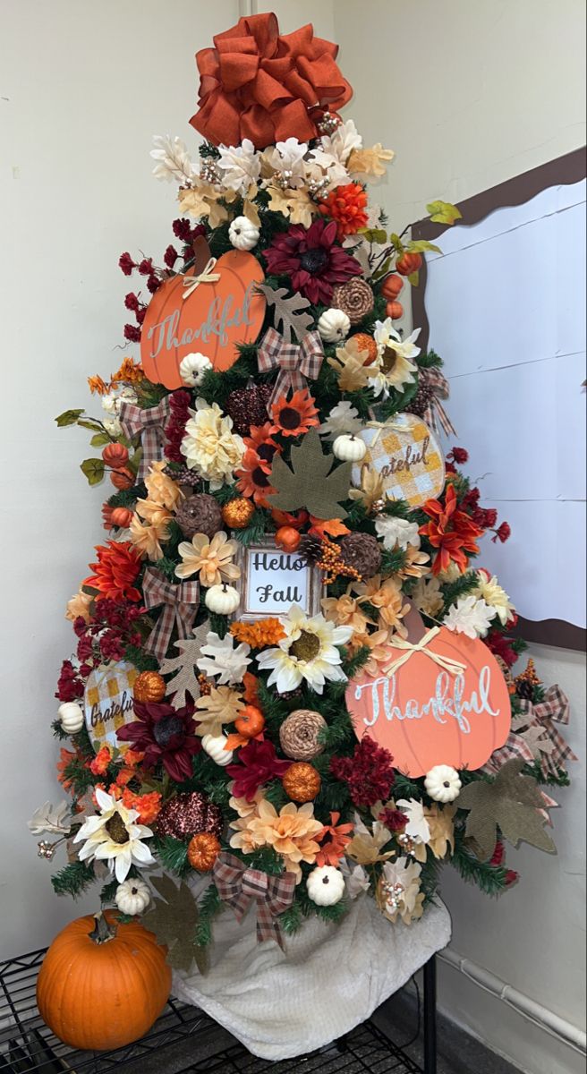 a decorated christmas tree with orange and white flowers, pumpkins and other holiday decorations