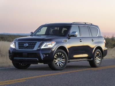 a black nissan suv is driving down the road