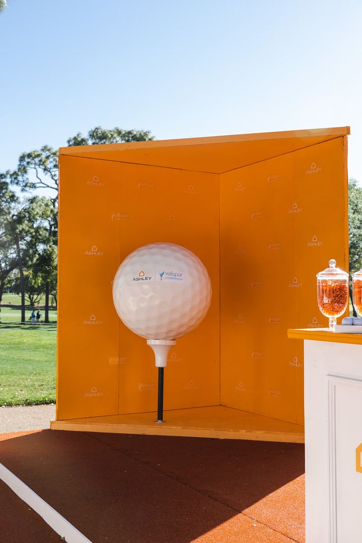 a white golf ball sitting on top of a wooden table next to a yellow box