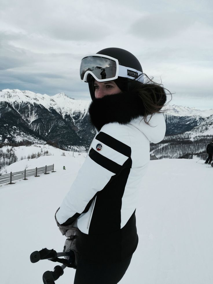 a woman standing on top of a snow covered slope with skis and goggles