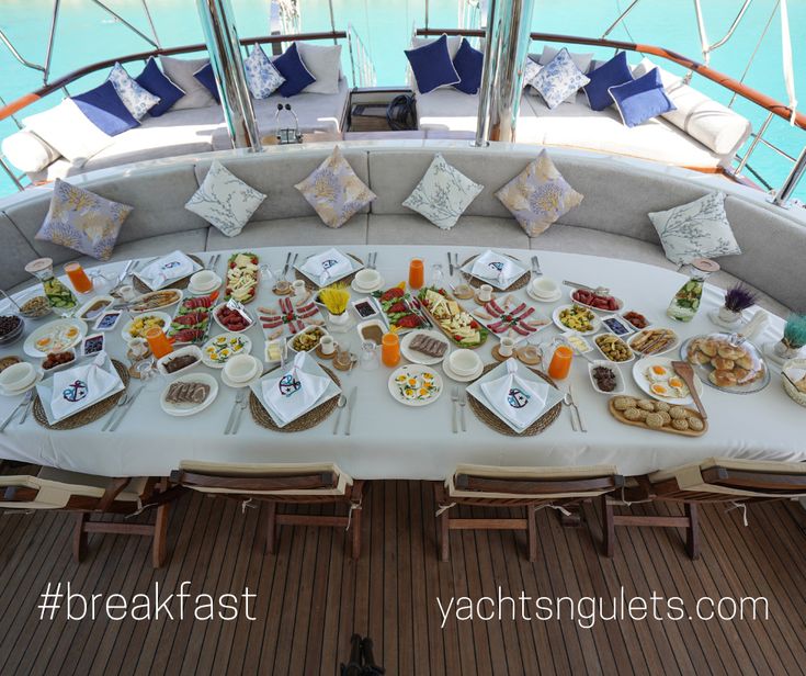 the table is full of food and drinks on it's own deck, overlooking the water