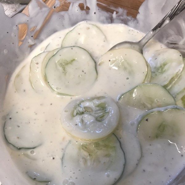 cucumbers are being prepared in a bowl with cream and sauce on the side