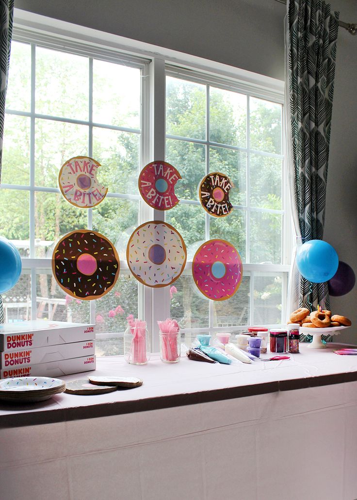 a table topped with donuts and balloons next to a window