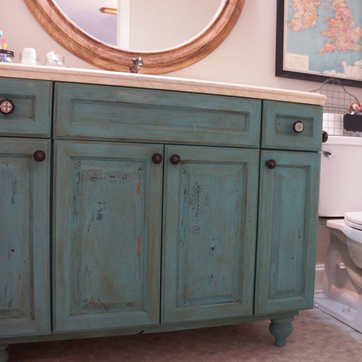 a bathroom with blue cabinets and a mirror above the toilet area is seen in this image