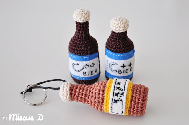 two crocheted wine bottles sitting on top of a table next to a keychain