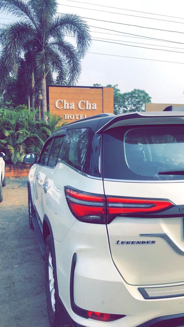 the rear end of a white car parked in front of a sign that reads cha cha hotel